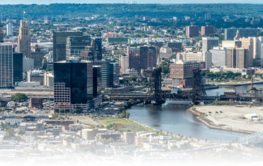 Aerial view of Essex County, NJ, showcasing a mix of urban buildings, waterways, and infrastructure under a clear sky.